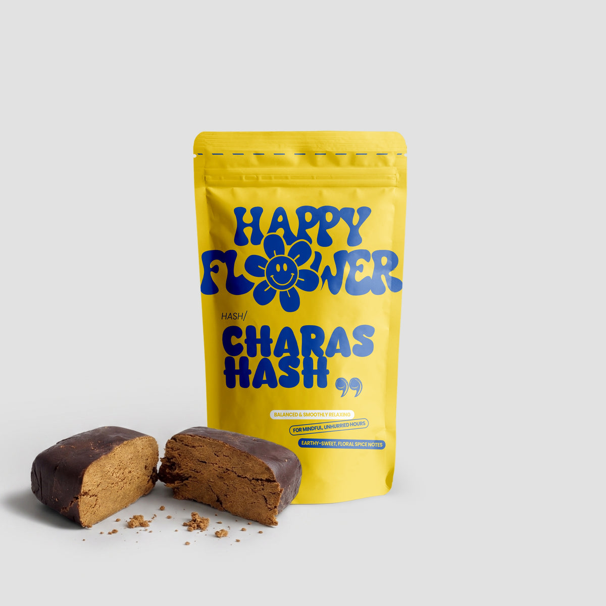 Happy Flower Charas Hash in gelber Standbeutel-Verpackung mit zwei angeschnittenen braunen Hasch-Stücken auf hellem Hintergrund.