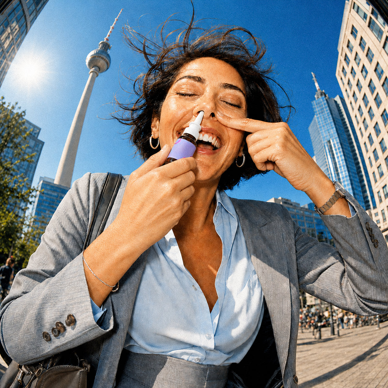 Lachende Businessfrau verwendet bei sonnigem Wetter ein 3-FPO Nasenspray von Happy Flower vor dem Berliner Fernsehturm.