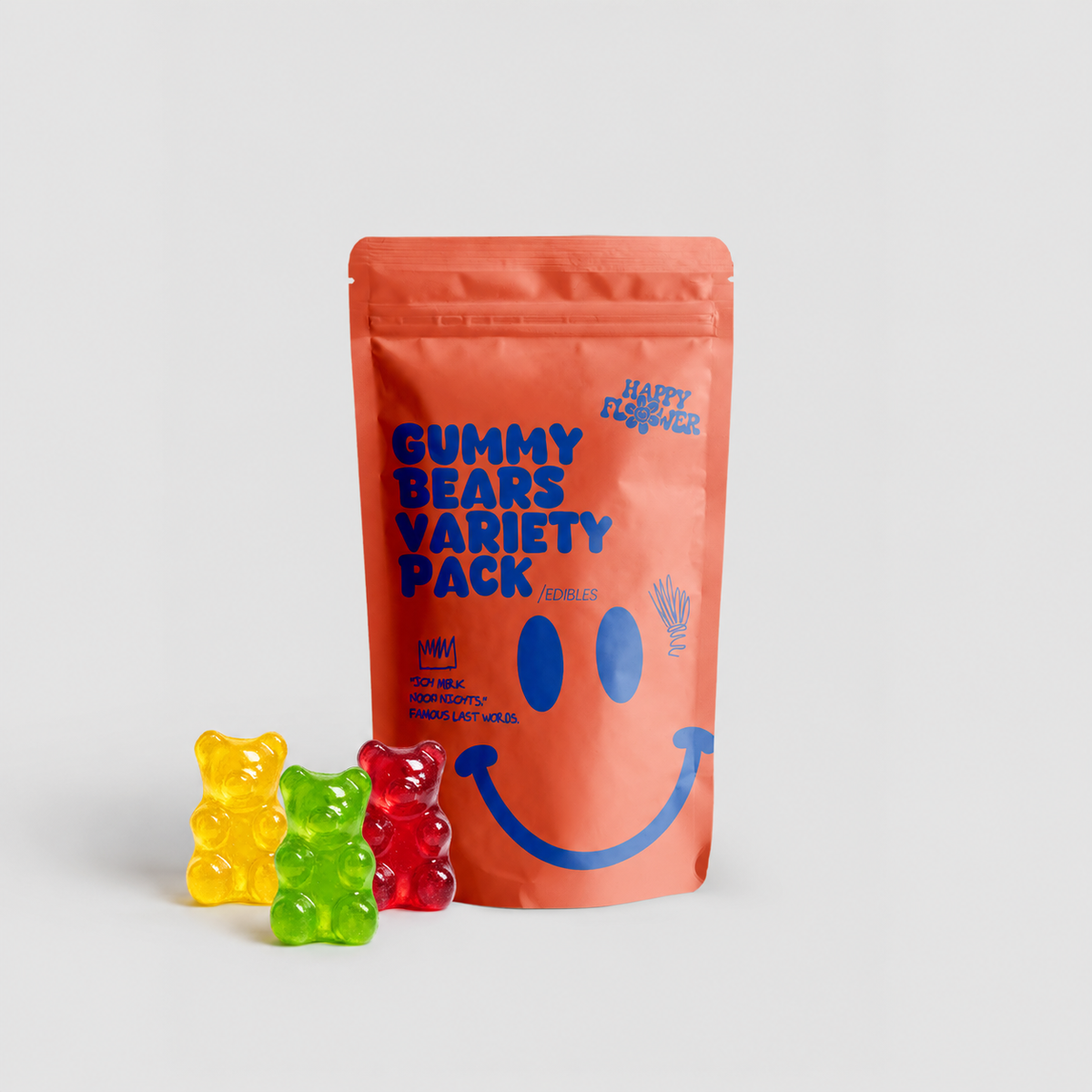 Happy Flower Gummy Bears Variety Pack Edibles in korallfarbener Standbeutel-Verpackung mit gelben, grünen und roten Gummibärchen im Vordergrund auf hellem Hintergrund.