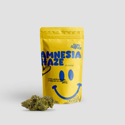 Happy Flower Amnesia Haze Flowers in gelber Standbeutel-Verpackung mit einer großen Cannabisblüte im Vordergrund auf hellem Hintergrund.