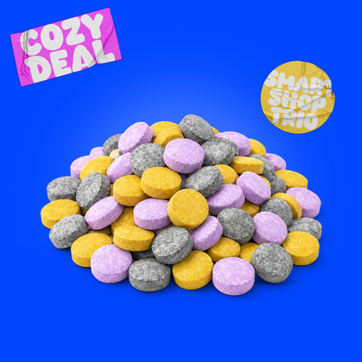 Haufen aus gelben 4-PRO-MET, lilafarbenen 3-FPO und grauen 1Fe-LSD Pellets auf weißem Hintergrund mit blauem „Cozy Deal´s“-Sticker.