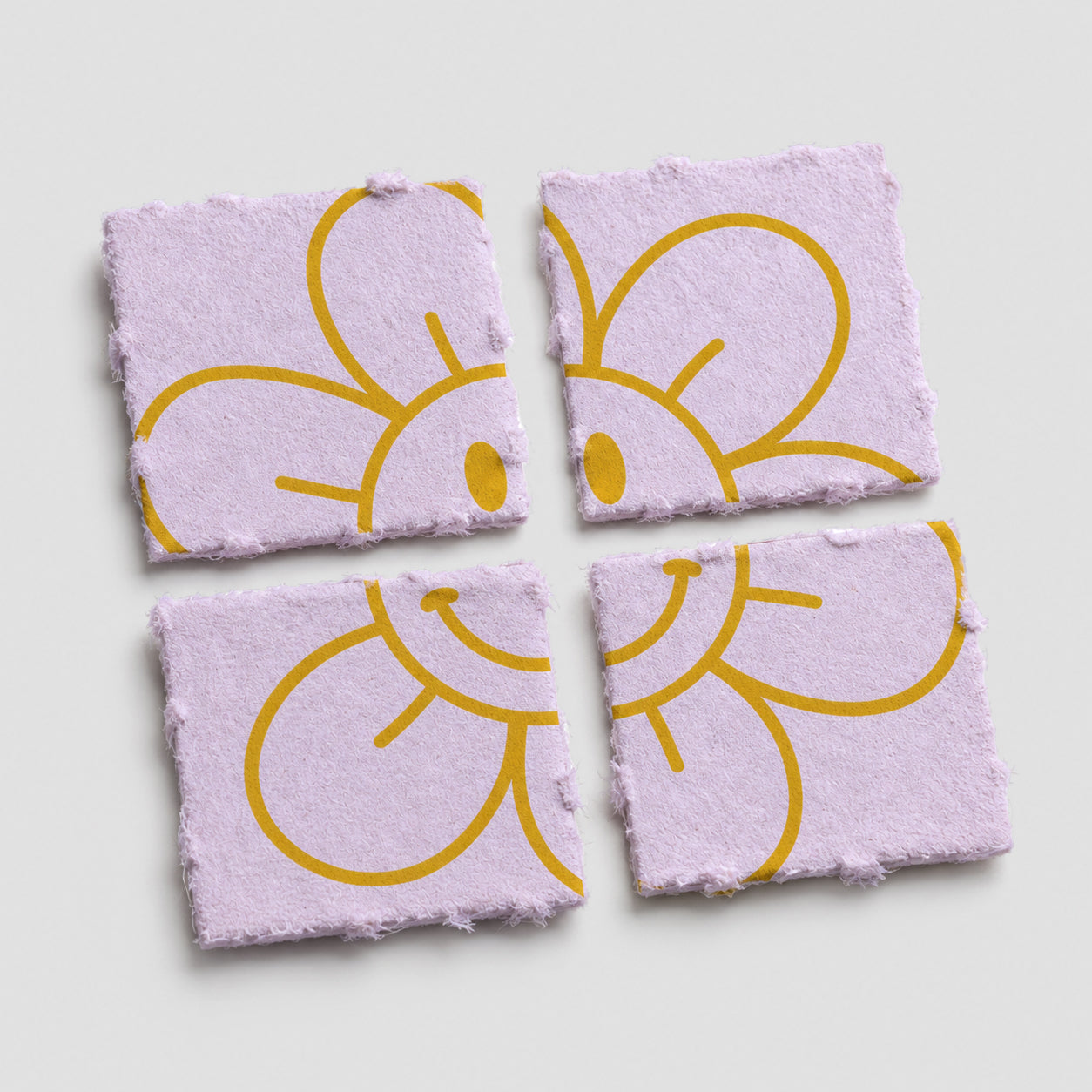 Vier quadratische, perforierte Blotter-Papiere in Helllila mit gelber, lächelnder Blumenillustration auf weißem Hintergrund.
